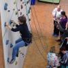 eine Frau klettert an der Kletterwand und wird dabei gesichert